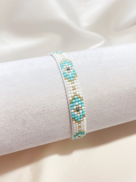 Pulsera tejida miyuki blanca con ojos turcos celestes