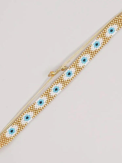 Pulsera tejida miyuki 6 filas dorada con ojos turcos blancos con celeste